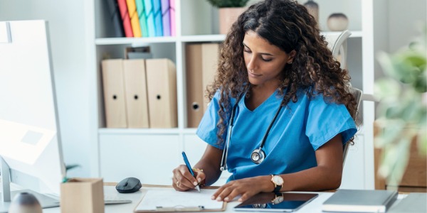 An advanced practice registered nurse doing paperwork at her desk.