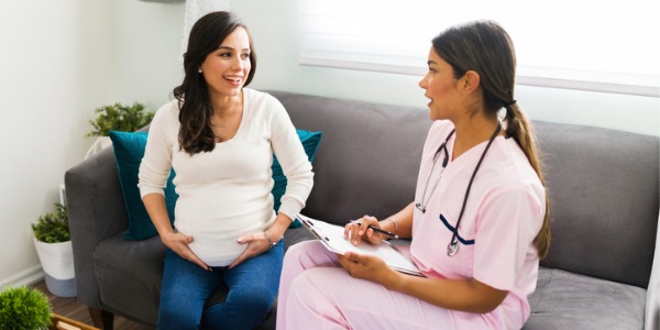 A certified nurse midwife talking to an expecting mother.