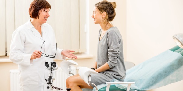 A female gynecologist talking to her patient in the examining room.
