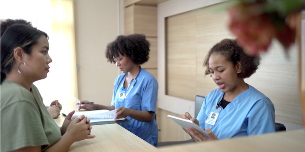 Two medical administrative assistants assisting patients .