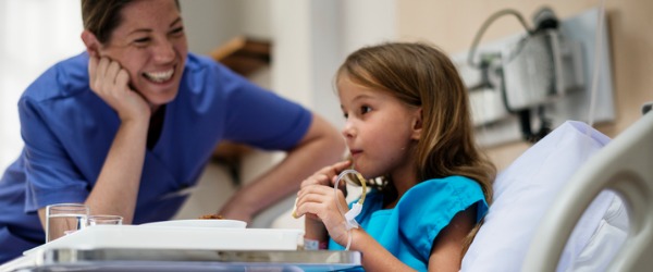 A licensed practical nurse smiling with one of her young patients.