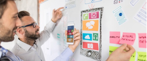 Two UX designers coming up with a design on a whiteboard.