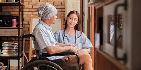 An oncology nurse sitting with a patient.